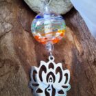 Pendentif avec sa perle aux couleurs de chakras et sa figurine avec fleur de lotus en position de yoga